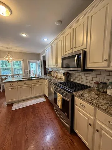 a kitchen with stainless steel appliances granite countertop a stove a sink and white cabinets