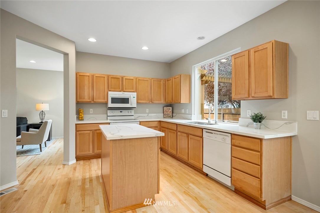 4918 Northeast 4th Place Renton, WA 98059 - Photo 8 of 33 a kitchen with stainless steel appliances a stove top oven a sink a refrigerator white cabinets and wooden floor