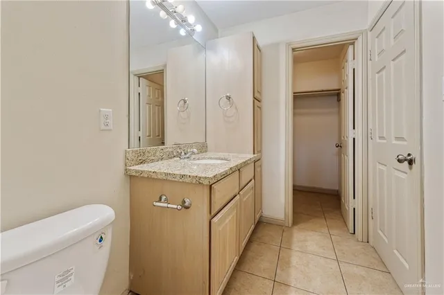 a bathroom with a granite countertop toilet sink and mirror