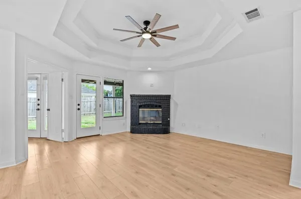 a view of an empty room with wooden floor and a fireplace