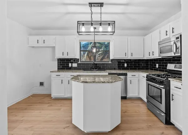 a kitchen with stainless steel appliances granite countertop a stove a sink and white cabinets