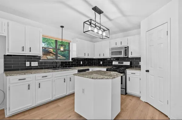 a kitchen with stainless steel appliances granite countertop a sink a stove a refrigerator and cabinets