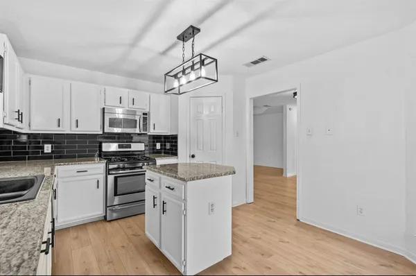 a kitchen with stainless steel appliances granite countertop a sink a stove a refrigerator with white cabinets