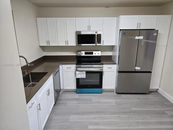 a kitchen with a stove a refrigerator and a microwave
