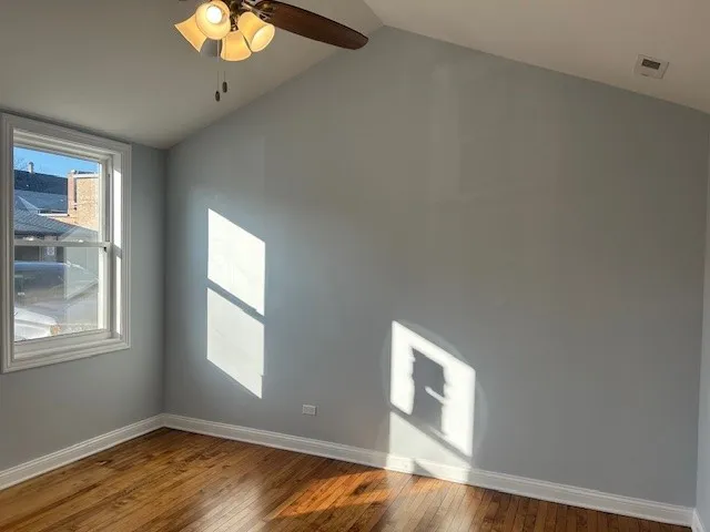 a view of an empty room with wooden floor and window