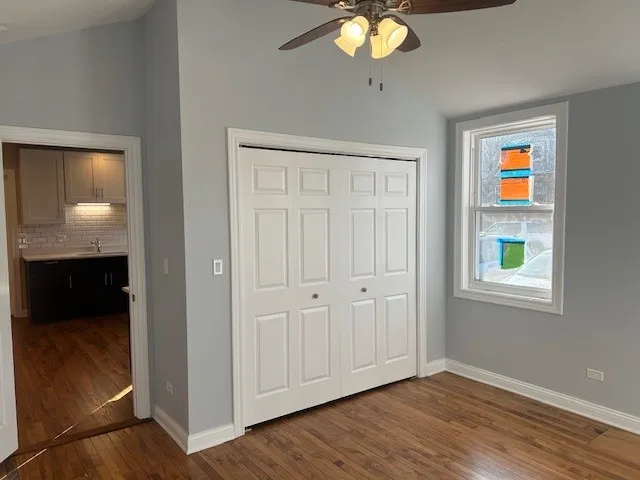 an empty room with wooden floor cabinet and windows
