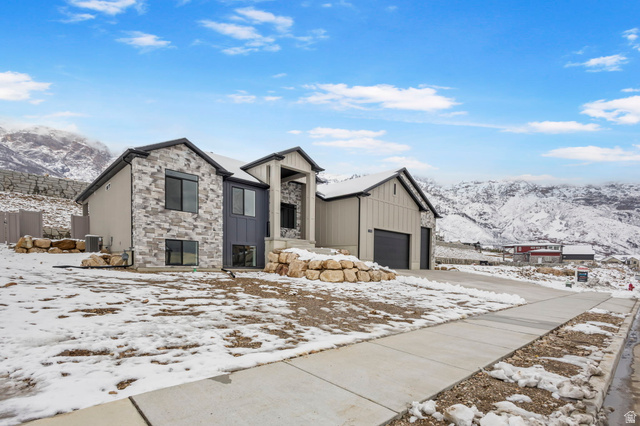 728 East Mountain Road North Ogden, UT 84414 - Photo 2 of 28 Modern architectural home featuring a multi-textured exterior, prominent stone accents, board and batten siding, dark-framed windows, and an integrated garage