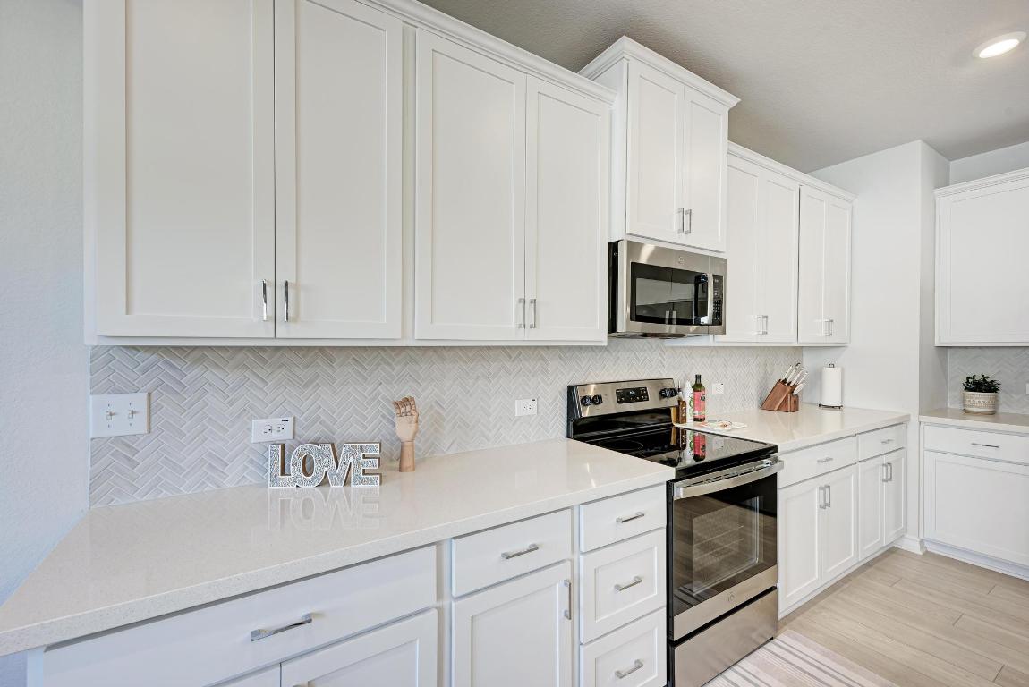 113 Rampart Loop Liberty Hill, TX 78642 - Photo 8 of 40 a kitchen with white cabinets and white appliances