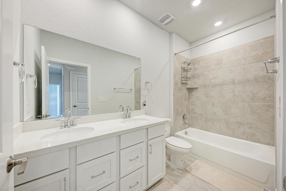 113 Rampart Loop Liberty Hill, TX 78642 - Photo 22 of 40 a bathroom with a double vanity sink toilet mirror and bathtub