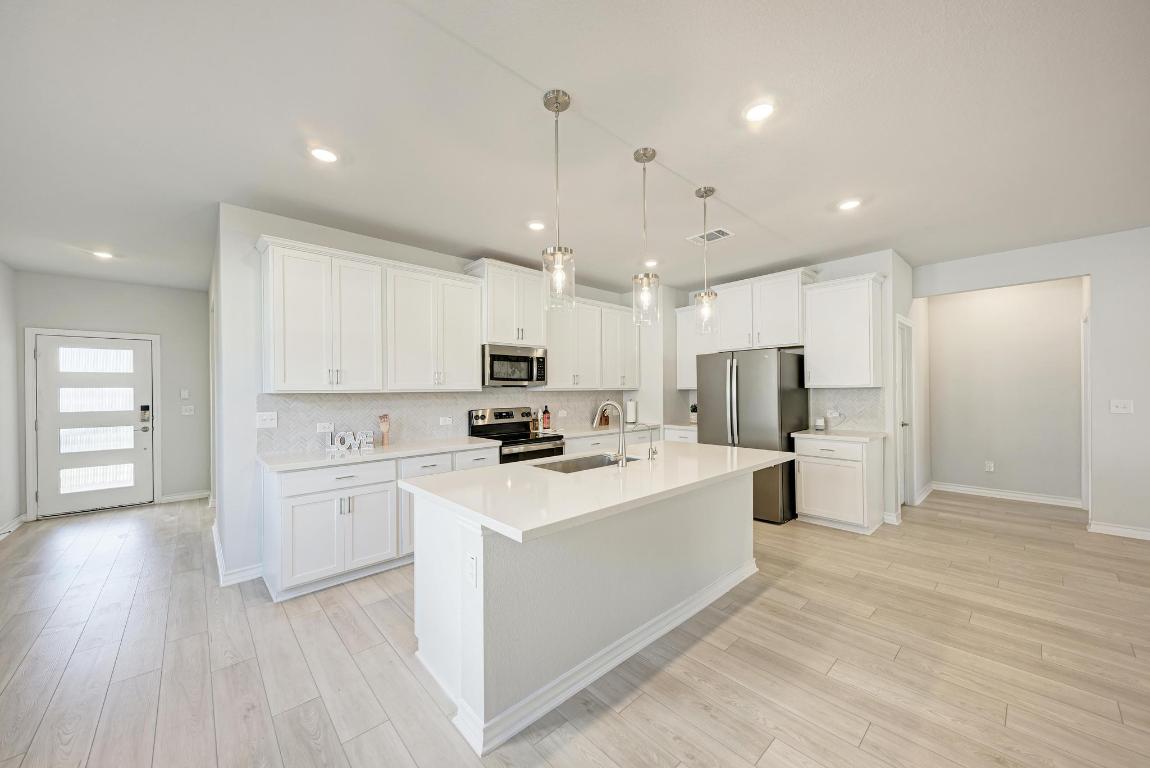 113 Rampart Loop Liberty Hill, TX 78642 - Photo 5 of 40 a kitchen with stainless steel appliances a refrigerator sink and microwave