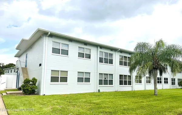 a front view of a house with a garden and trees