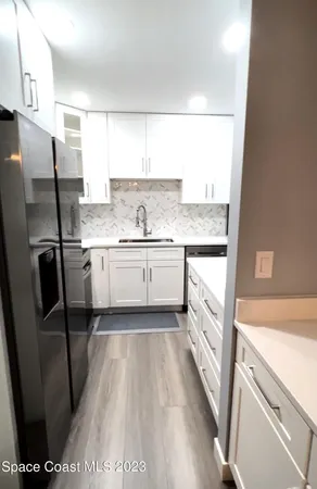 a kitchen with a sink a refrigerator a stove top oven and cabinets