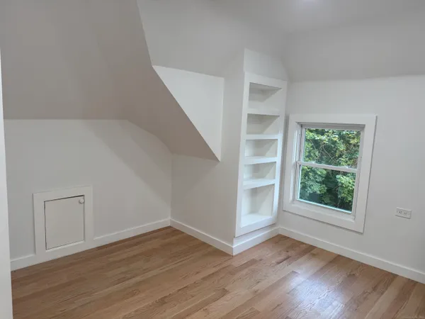 a view of an empty room with a window and wooden floor