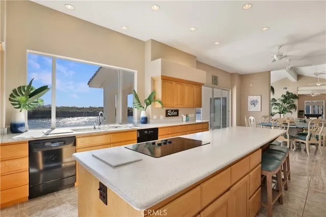 a large kitchen with a large counter top space a sink stainless steel appliances and cabinets