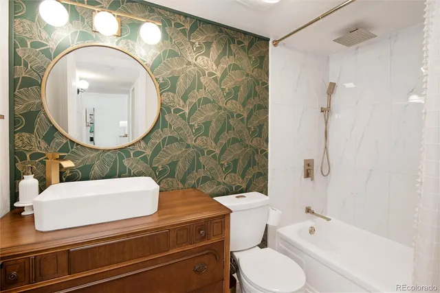 a bathroom with a toilet sink mirror vanity and shower