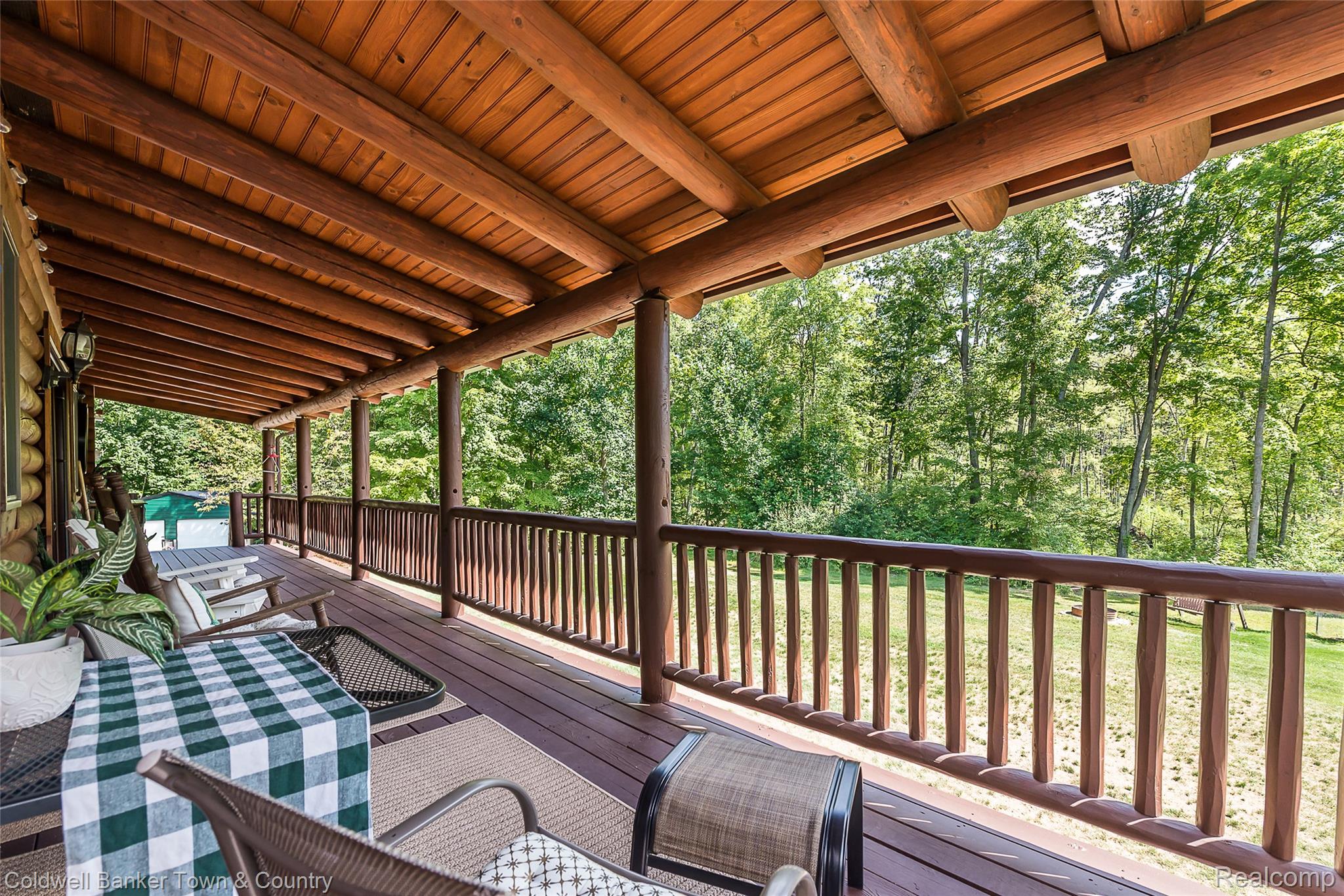 7023 Munsell Road Howell, MI 48843 - Photo 17 of 55 Expansive covered porch featuring a wood-plank ceiling, exposed log beams, sturdy log columns, wood railings, and composite decking