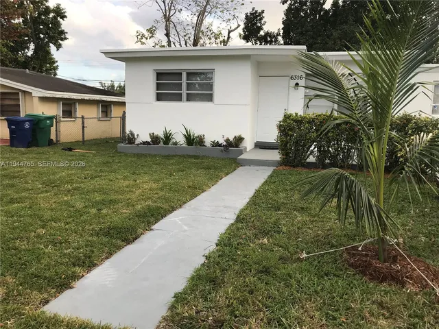 a backyard of a house with potted plants and large tree