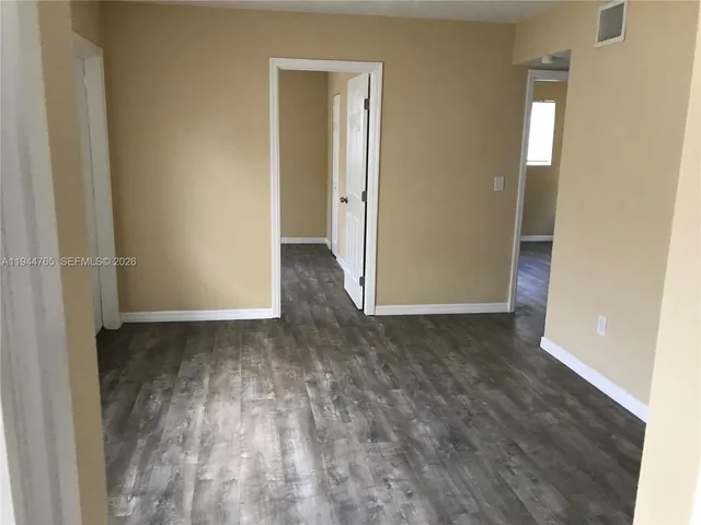 a view of an empty room with wooden floor and closet
