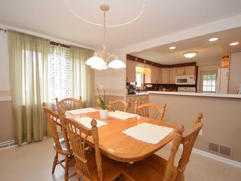 Dining Room. The dining room has chair rail trim, a ceiling medallion, and an attractive chandelier. The large window allows sunlight to fill the room, creating a cheerful atmosphere in this space.