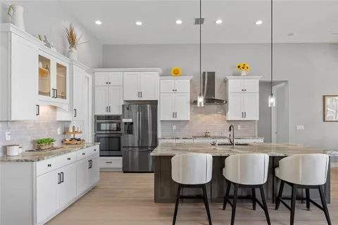 a kitchen with stainless steel appliances kitchen island granite countertop a sink refrigerator and cabinets