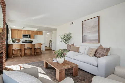 a living room with furniture kitchen view and a table