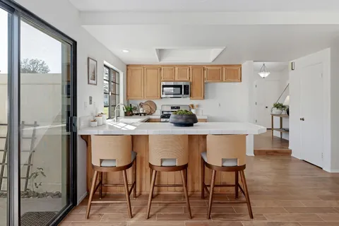 a kitchen with stainless steel appliances granite countertop a table chairs refrigerator and cabinets