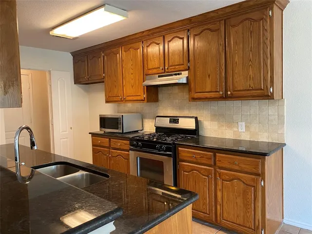 a kitchen with granite countertop a sink a stove and cabinets