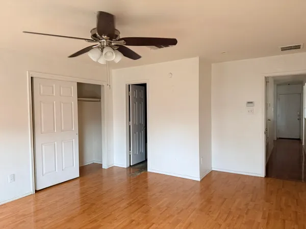 a view of empty room with wooden floor and ceiling fan