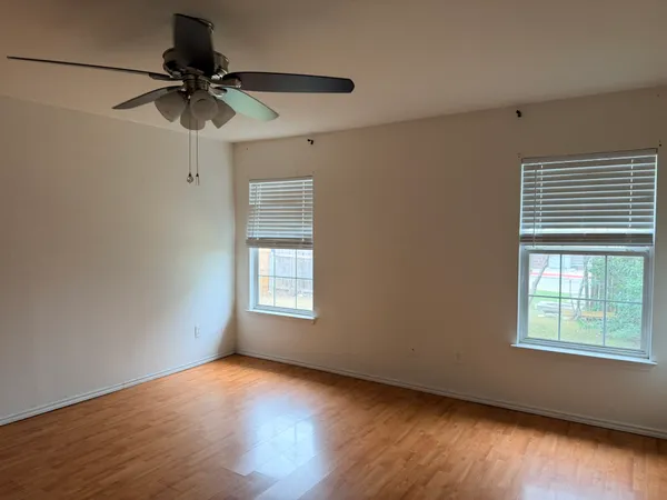 a view of an empty room with a window and wooden floor
