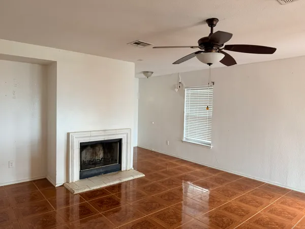 a view of an empty room with a fireplace and a fan