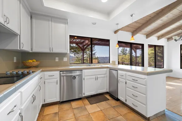 a kitchen with granite countertop white cabinets white appliances a sink and a large window