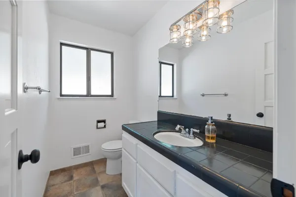 a bathroom with a granite countertop sink a toilet and a mirror