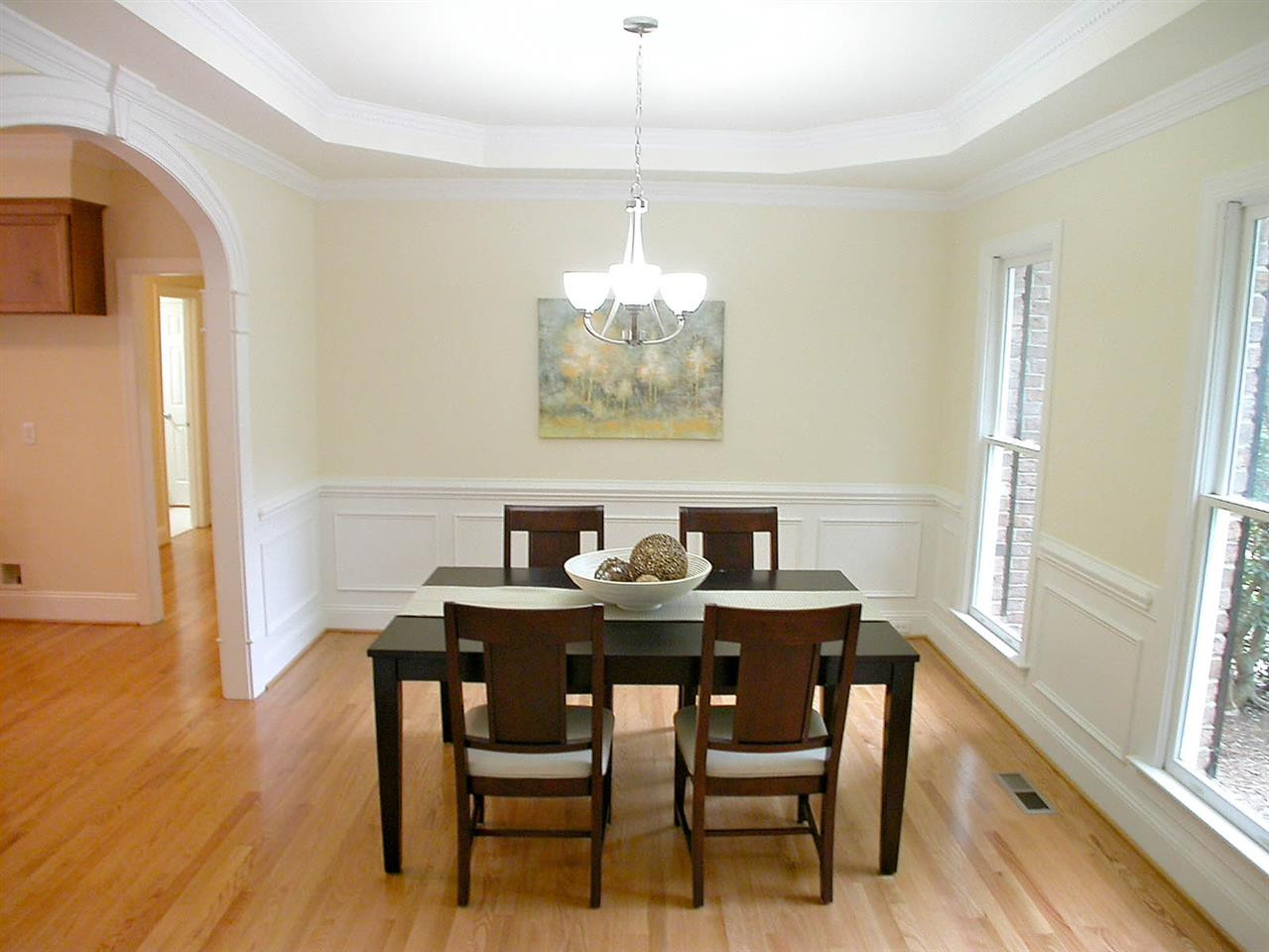 705 Porchlamp Court Raleigh, NC 27615 - Photo 6 of 25 Formal dining room with tray ceiling, chandelier, hardwood floors & arched doorway to kitchen & foyer. Dining Room
