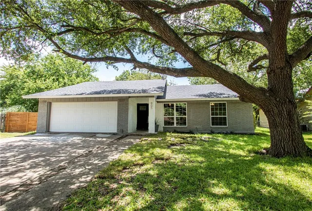 a view of a house with a tree in front of it