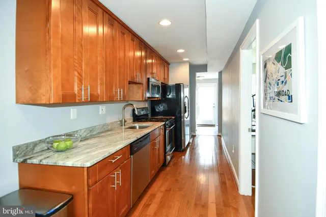 a kitchen with stainless steel appliances granite countertop a sink a stove and a refrigerator