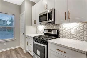 6814 Dumble Street, Unit B Houston, TX 77021 - Photo 4 of 22 a kitchen with stainless steel appliances a stove a microwave and white cabinets
