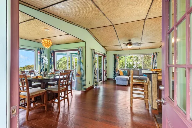 a kitchen with stainless steel appliances granite countertop a stove a refrigerator a couch and a dining table with wooden floor