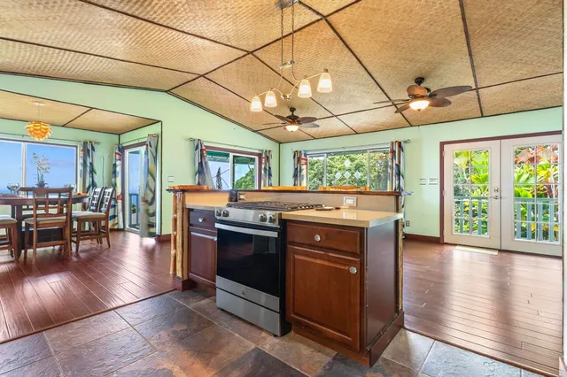 a kitchen with stainless steel appliances granite countertop a stove a refrigerator a kitchen island a blue cabinets and wooden floor