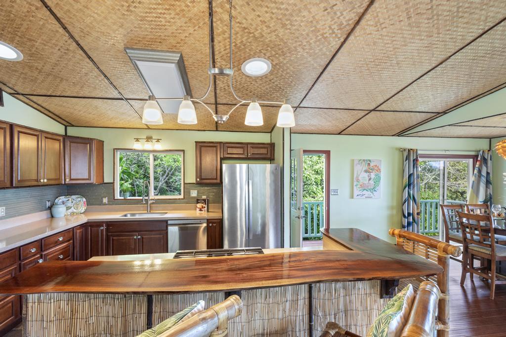 87-2707 Hawaii Belt Road Captain Cook, HI 96704 - Photo 13 of 30 a kitchen with stainless steel appliances granite countertop a stove a refrigerator a kitchen island a blue cabinets and wooden floor