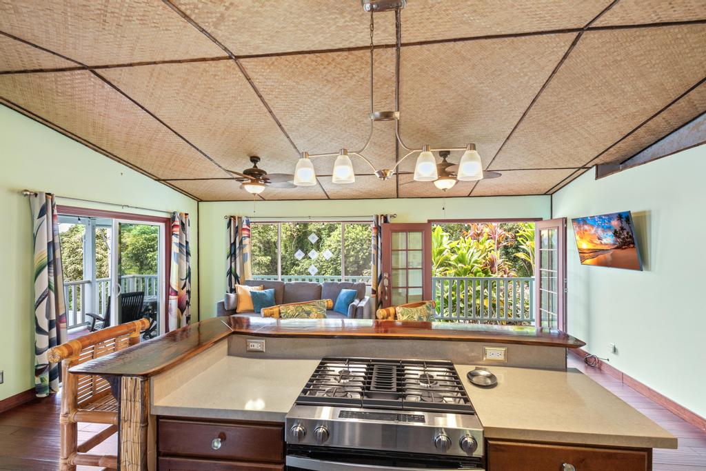 87-2707 Hawaii Belt Road Captain Cook, HI 96704 - Photo 15 of 30 a kitchen with a stove a sink dishwasher and a dining table with garden view