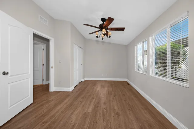 a view of empty room with wooden floor and fan