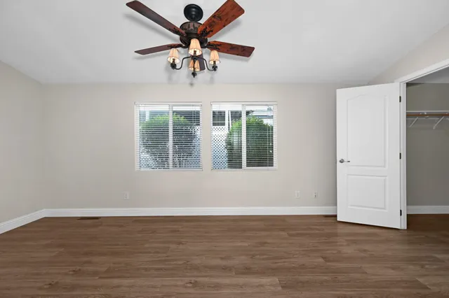 a view of an empty room with a window and wooden floor