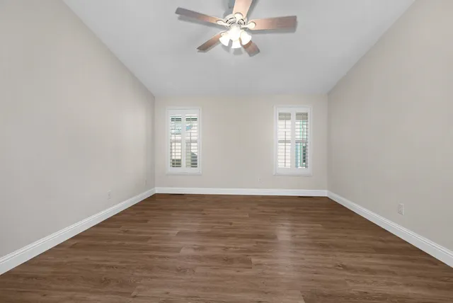 a view of an empty room with window and wooden floor