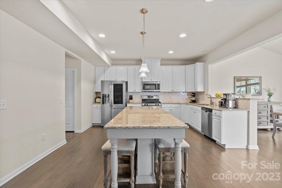1662 Callahan Road Fort Mill, SC 29715 - Photo 13 of 42 a large kitchen with kitchen island a stove a sink a refrigerator and white cabinets with wooden floor