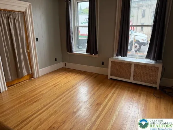 an empty room with wooden floor and windows