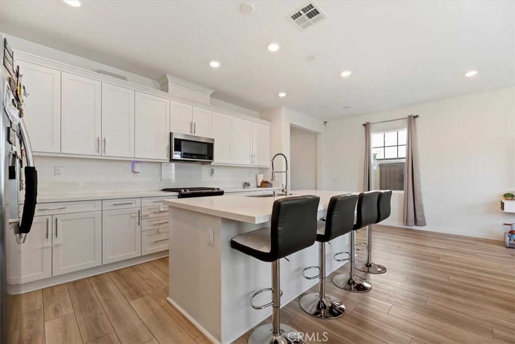 20911 Jennings Way Newhall, CA 91321 - Photo 13 of 47 a kitchen with stainless steel appliances granite countertop a stove a sink a refrigerator white cabinets and wooden floor