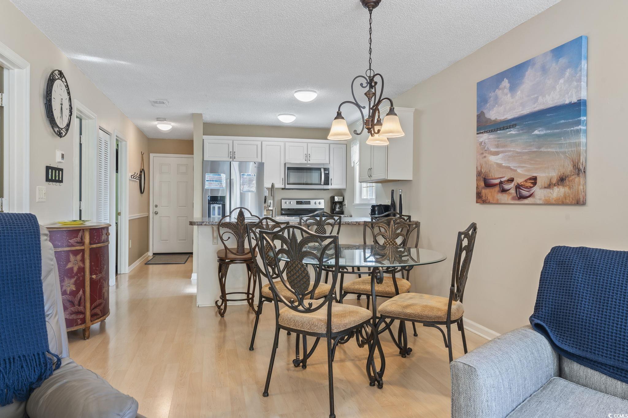 1425 North Waccamaw Drive, Unit 123 Murrells Inlet, SC 29576 - Photo 26 of 39 Dining room with a textured ceiling, light wood finished floors, and a chandelier