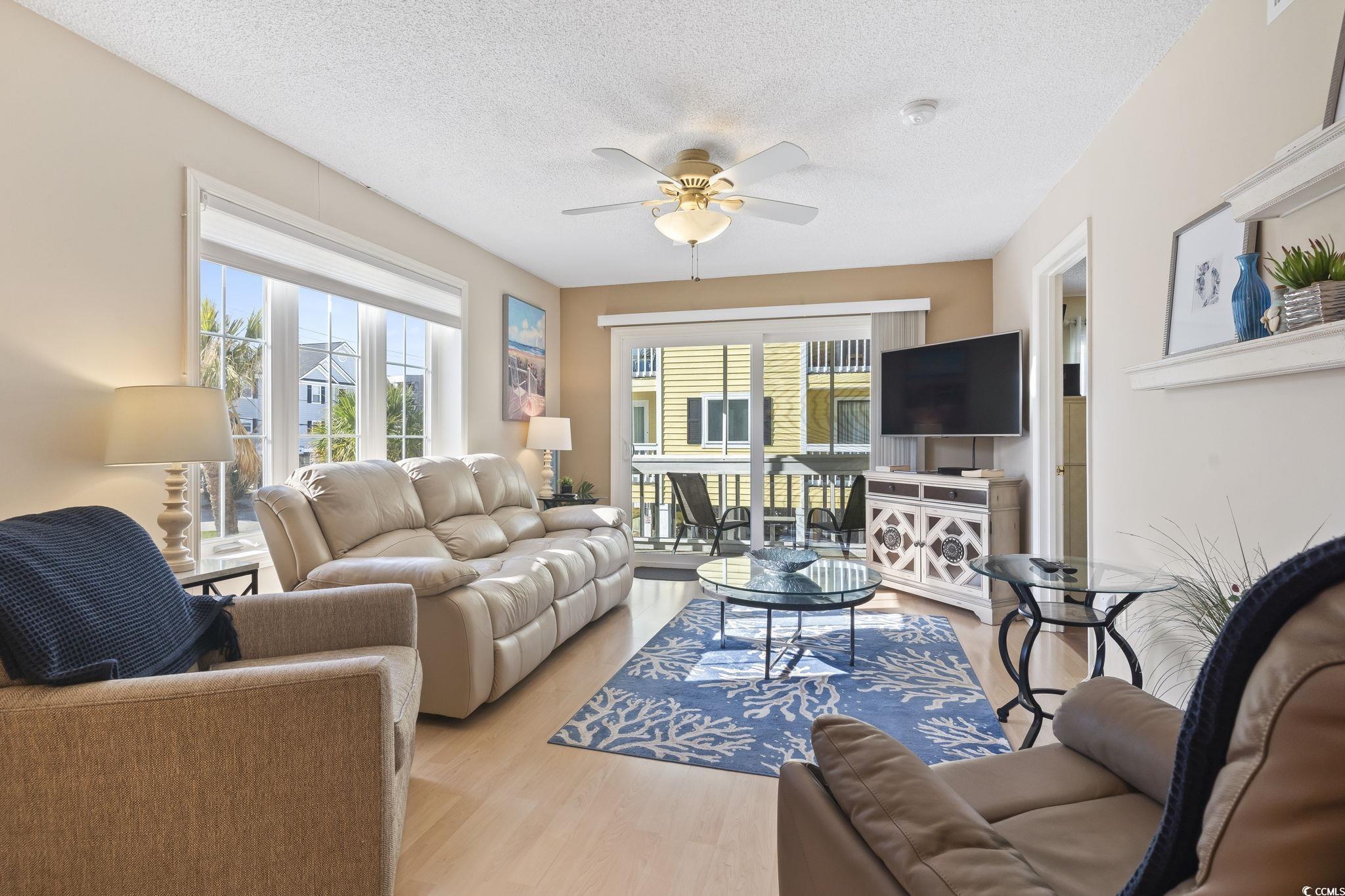 1425 North Waccamaw Drive, Unit 123 Murrells Inlet, SC 29576 - Photo 3 of 39 Living area featuring a textured ceiling, a ceiling fan, and light wood finished floors