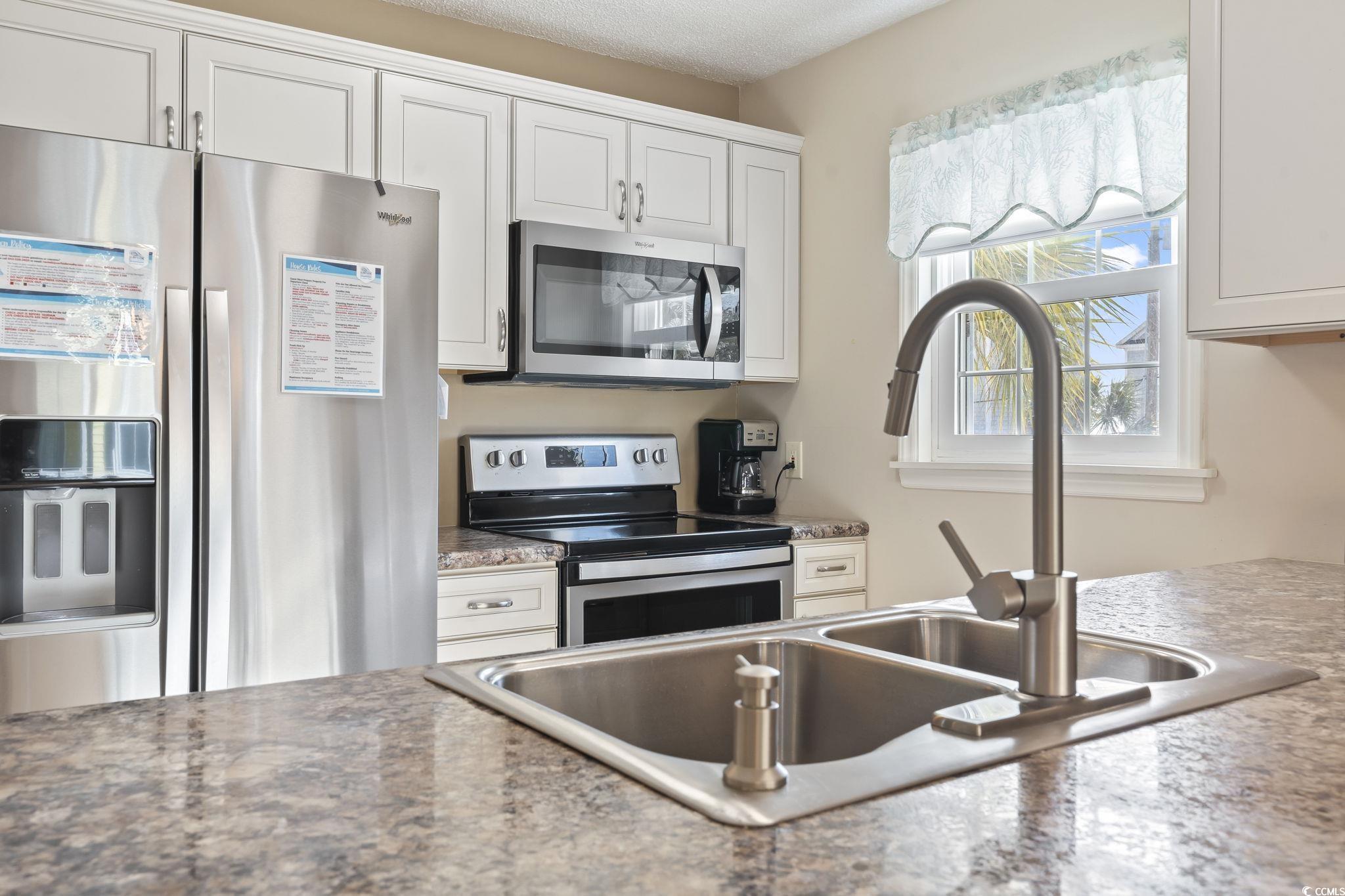 1425 North Waccamaw Drive, Unit 123 Murrells Inlet, SC 29576 - Photo 8 of 39 Kitchen with stainless steel appliances, white cabinets, and a textured ceiling