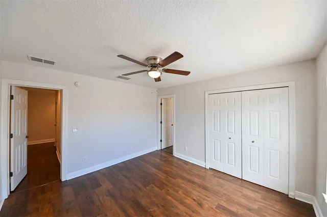 an empty room with wooden floor fan and windows